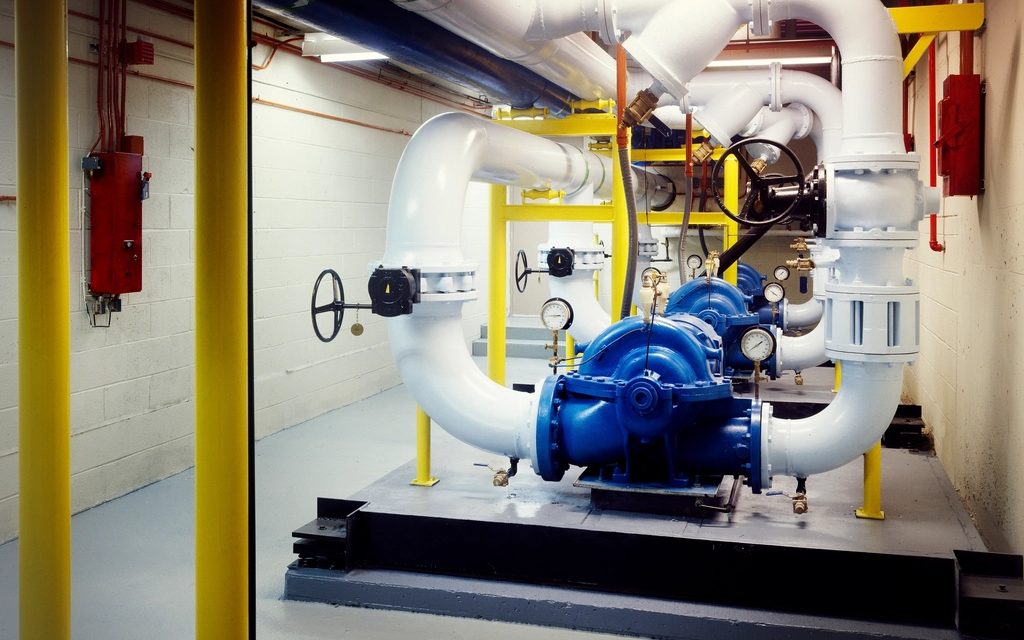Blue centrifugal pumps and gauges in a mechanical room.